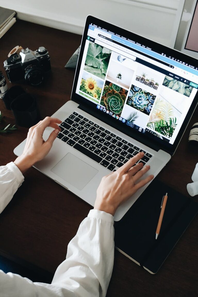 Person working on laptop with film camera nearby. Perfect for technology and lifestyle themes.